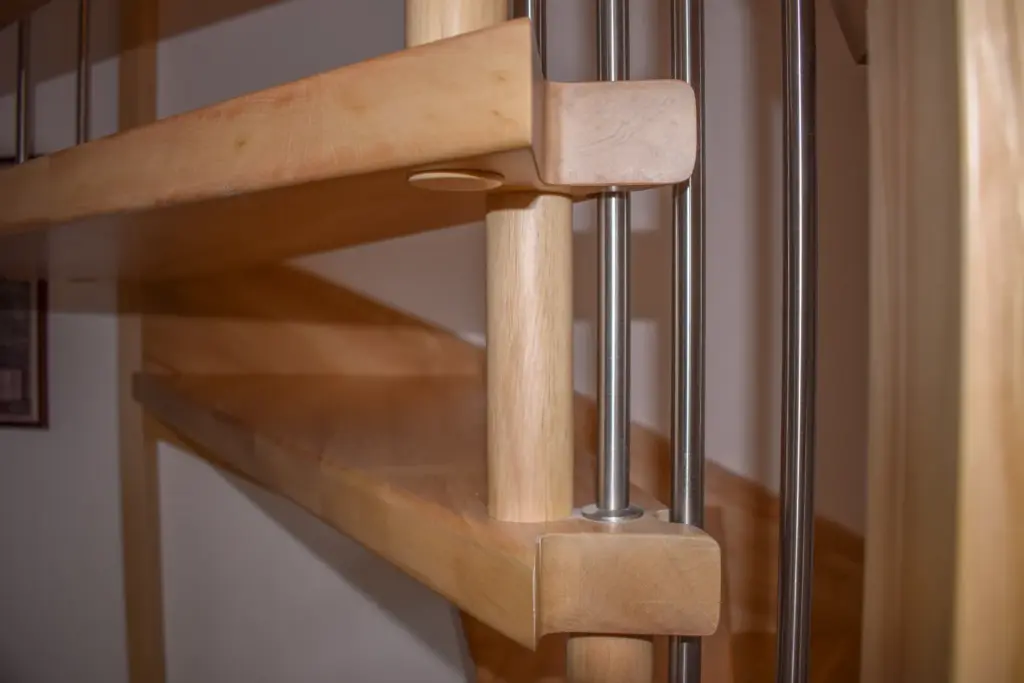 Nahaufnahme einer modernen Holztreppe mit Metallgeländer, die die klaren Linien und die glatte Oberfläche der hellen Holzstufen und der Tragkonstruktion zeigt.