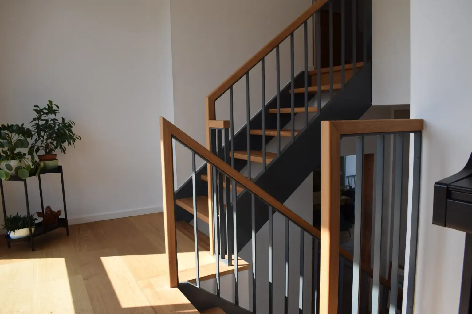 Design-Metalltreppe in Dunkelgrau mit Holzstufen.