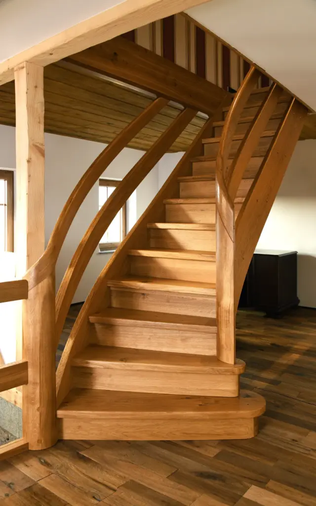 Schöne, rustikale Treppe aus Holz mit im Raum. Geschwungene Treppe mit ebenfalls geschwungenen Handlauf.