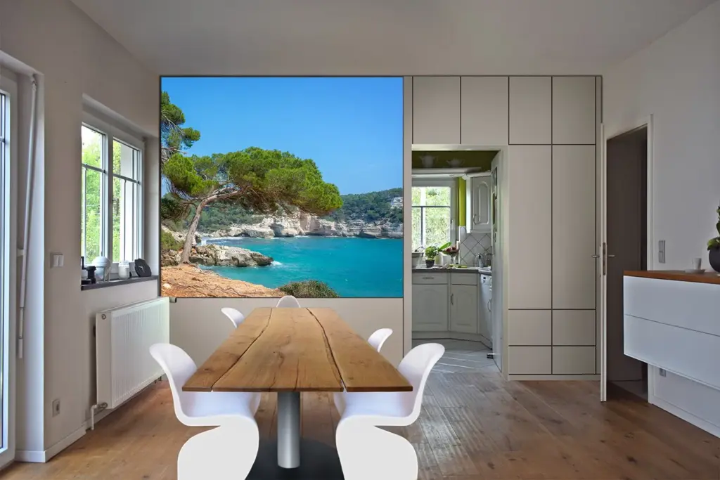 Modernes Esszimmer mit Holztisch und weißen Stühlen; ein großes Wandgemälde zeigt eine malerische Küstenlandschaft mit türkisfarbenem Wasser, felsigen Klippen und einem grünen Baum, der die Illusion eines Fensters zum Meer vermittelt.