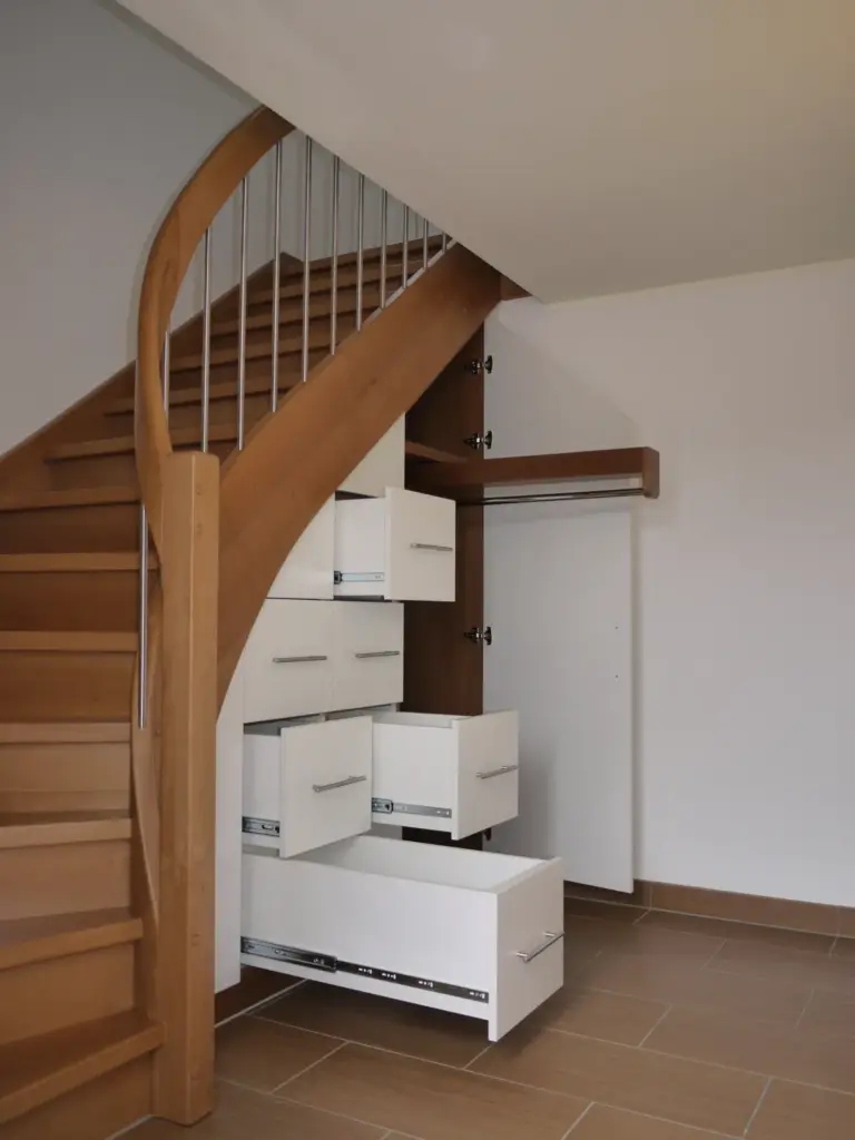 Eine Holztreppe mit mehreren weißen Schubladen und einem darunter eingebauten Schrank, der den Stauraum im Bereich unter der Treppe maximiert.
