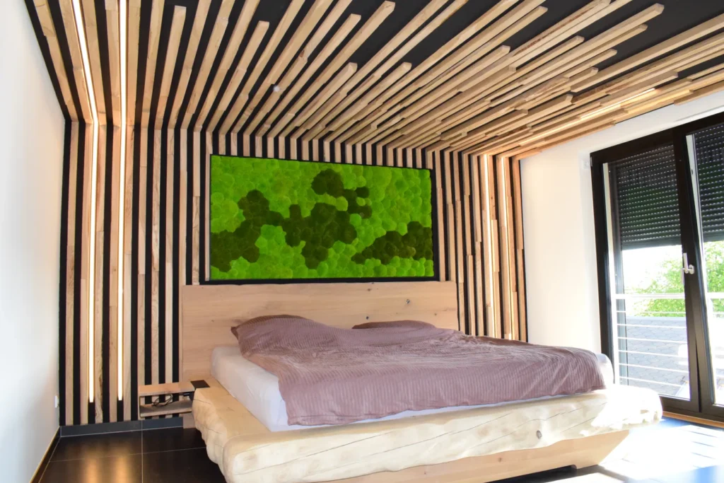 Ein modernes Schlafzimmer mit einem Holzbett, rosa Bettwäsche und einzigartigen Holzlatten an Wand und Decke. Über dem Bett hängt ein grünes Kunstwerk mit Struktur, und große Fenster lassen Tageslicht herein.