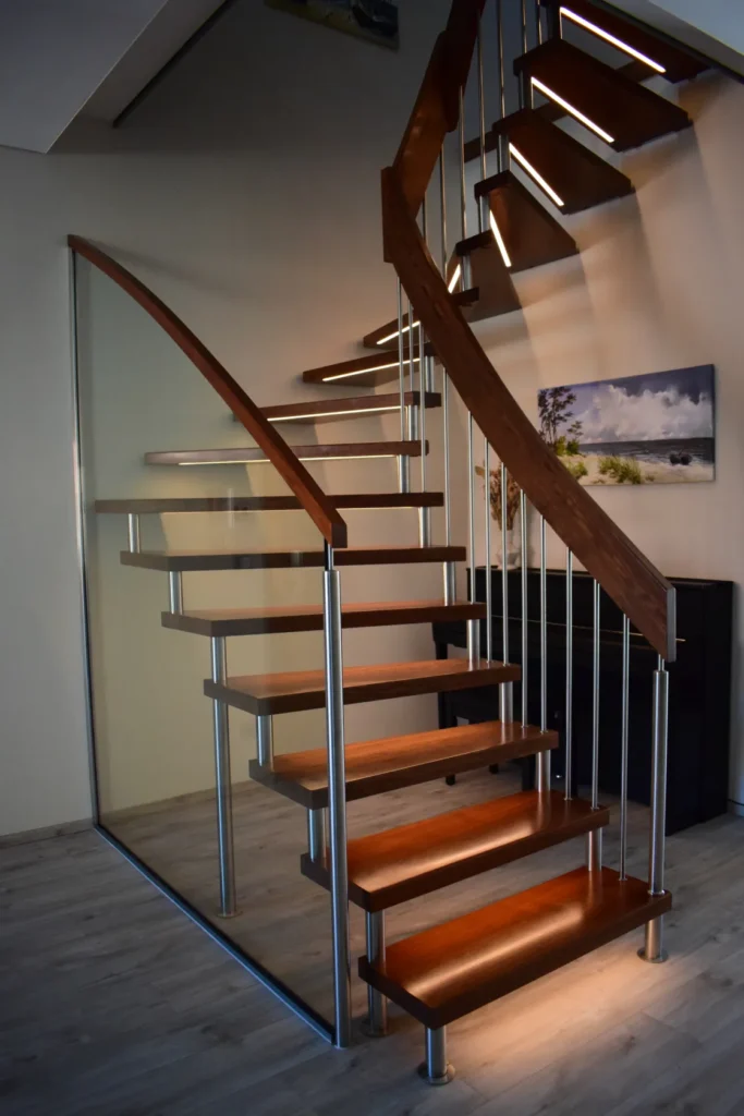 Eine moderne Holzwendeltreppe mit Metallgeländern und integrierter LED-Beleuchtung, umgeben von Glaspaneelen, in einem stilvollen Raum mit hellem Holzboden und Wandkunst.